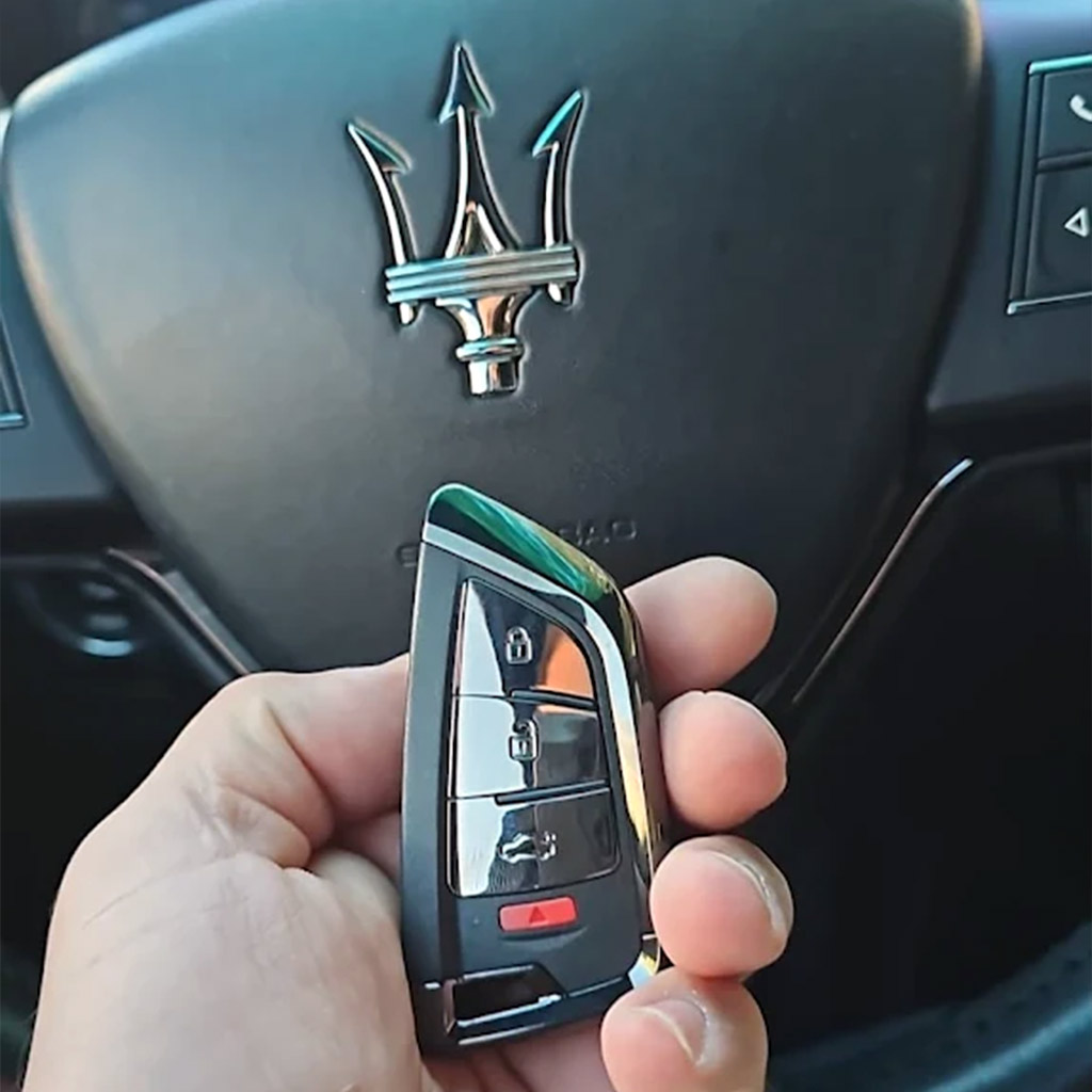 Locksmith holding a Maserati car key inside the vehicle during a key replacement service in Panama City Beach, FL